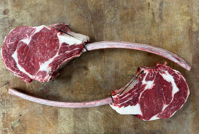 Two long-bone lamb chops on a wooden board