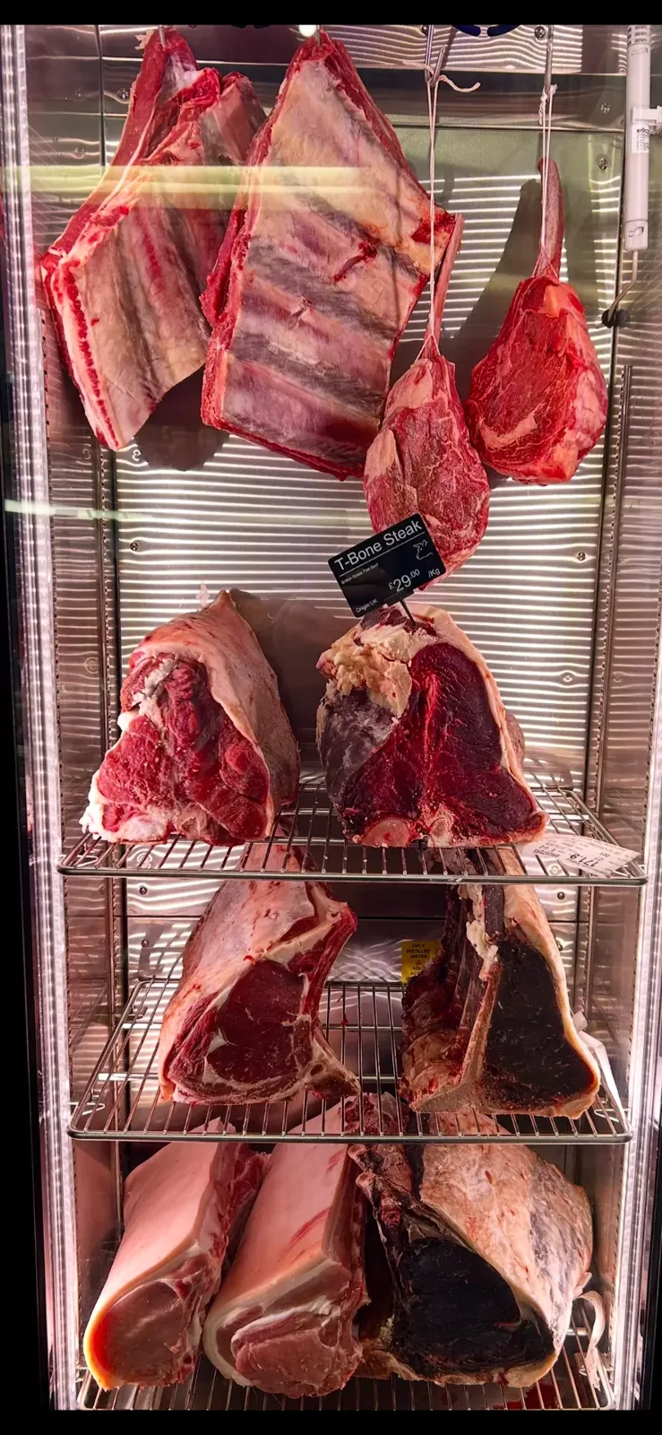 Beef ribs and steak cuts dry-aging in the illuminated cabinet at Lee’s Sandbach butcher’s