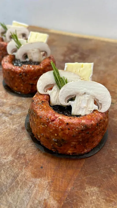 Oven-ready meat portions topped with mushrooms, cheese and herbs